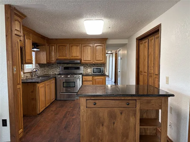 a kitchen with stainless steel appliances granite countertop a stove a sink and a refrigerator