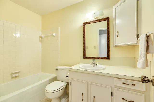 a bathroom with a granite countertop sink a toilet a mirror and shower