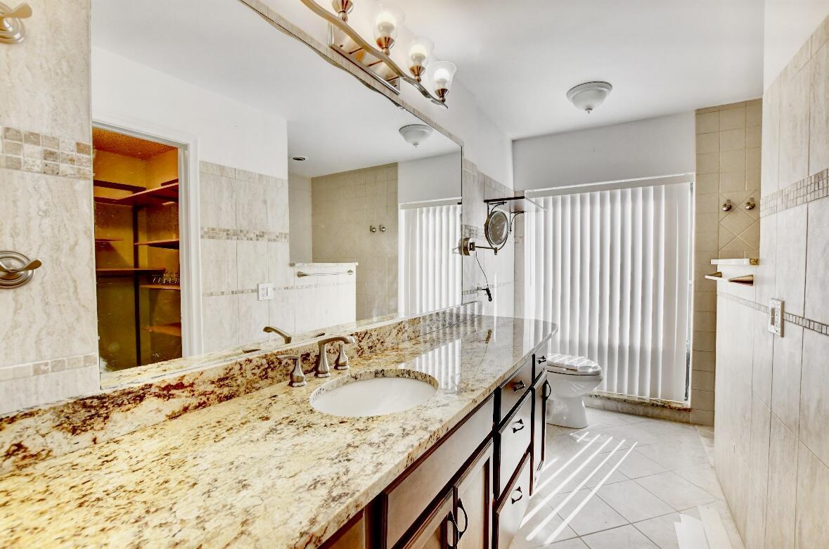 17768 Maplewood Drive Boca Raton, FL 33487 - Photo 31 of 50 a bathroom with a granite countertop sink a mirror and shower