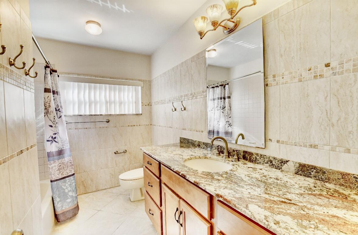 17768 Maplewood Drive Boca Raton, FL 33487 - Photo 32 of 50 a bathroom with a granite countertop sink toilet and shower