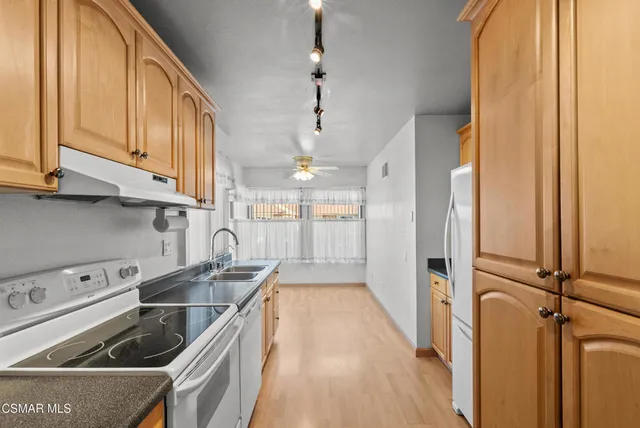 a kitchen with stainless steel appliances granite countertop a refrigerator a stove and a wooden floors