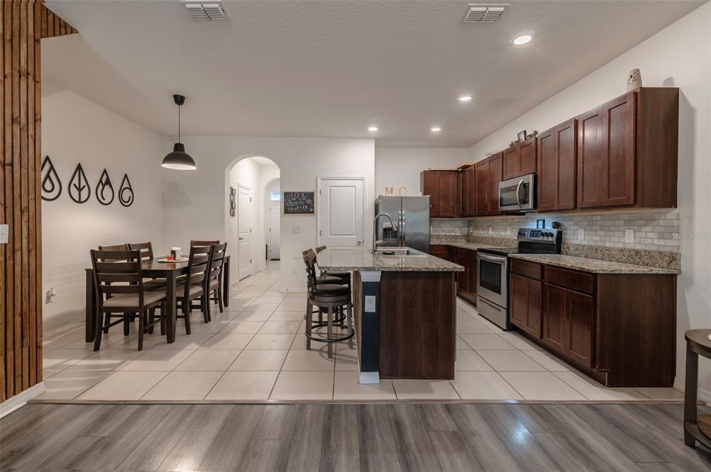 3327 Pleasant Willow Court Brandon, FL 33511 - Photo 11 of 28 a kitchen with stainless steel appliances granite countertop a stove top oven a sink dishwasher a dining table and chairs with wooden floor