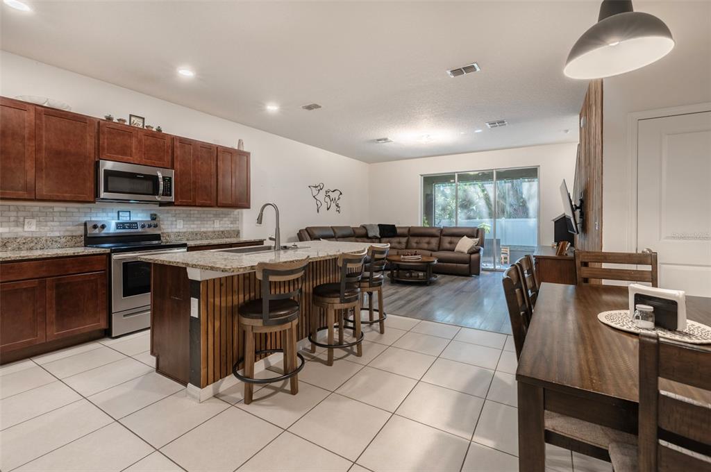 3327 Pleasant Willow Court Brandon, FL 33511 - Photo 6 of 28 a kitchen with stainless steel appliances granite countertop a stove a sink a microwave a dining table and chairs