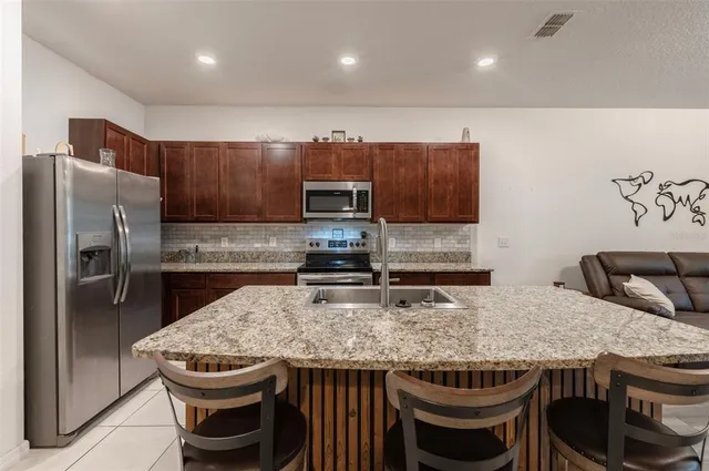 a kitchen with stainless steel appliances granite countertop a table chairs sink refrigerator and microwave