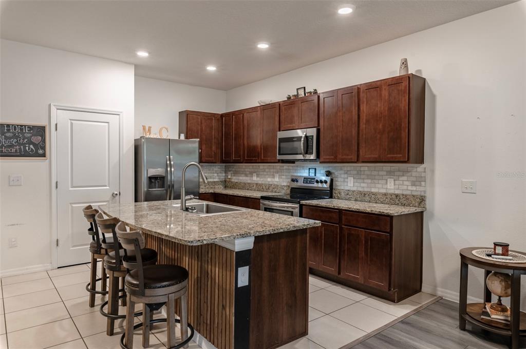 3327 Pleasant Willow Court Brandon, FL 33511 - Photo 9 of 28 a kitchen with stainless steel appliances granite countertop a table chairs sink refrigerator and microwave