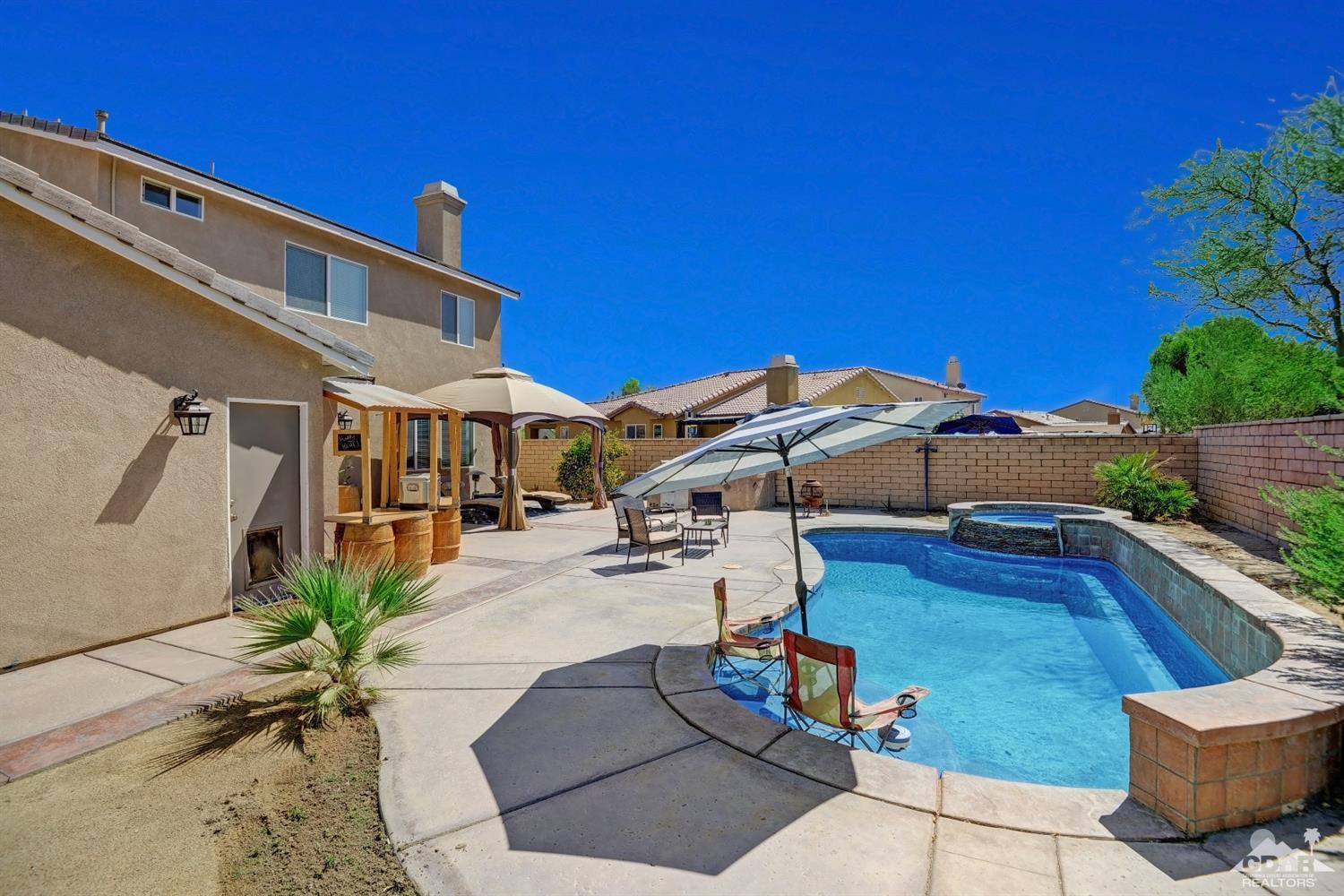 37773 Caprice Drive Indio, CA 92203 - Photo 2 of 26 a view of a patio with couches and table and chairs under an umbrella