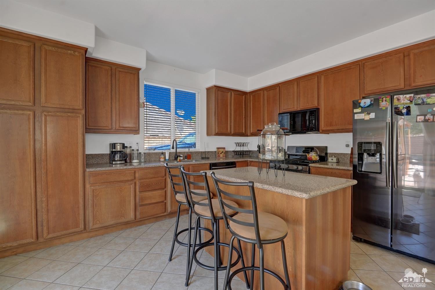 37773 Caprice Drive Indio, CA 92203 - Photo 7 of 26 a kitchen with a refrigerator a stove top oven a sink and cabinets