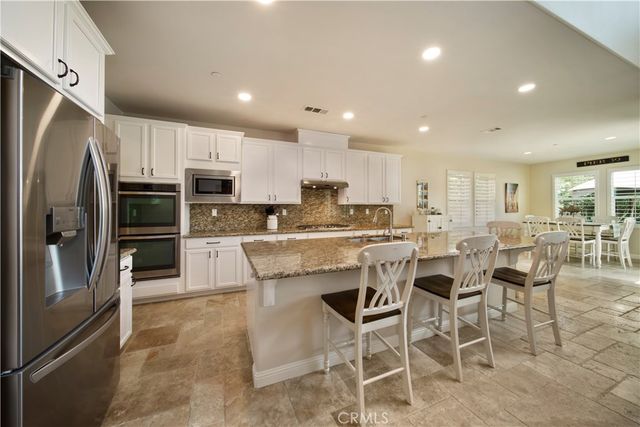 a kitchen with stainless steel appliances kitchen island granite countertop a refrigerator and a stove top oven
