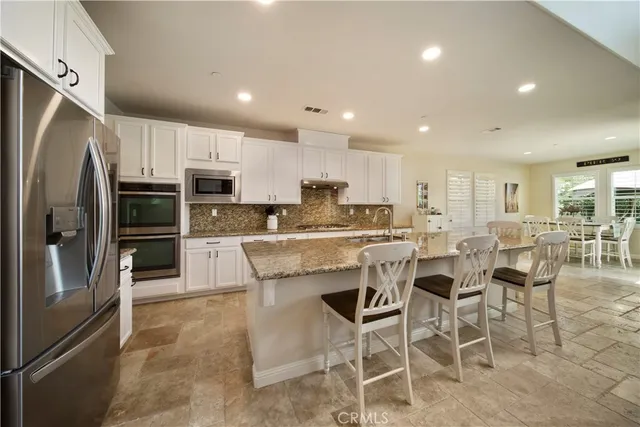 a kitchen with stainless steel appliances kitchen island granite countertop a refrigerator and a stove top oven