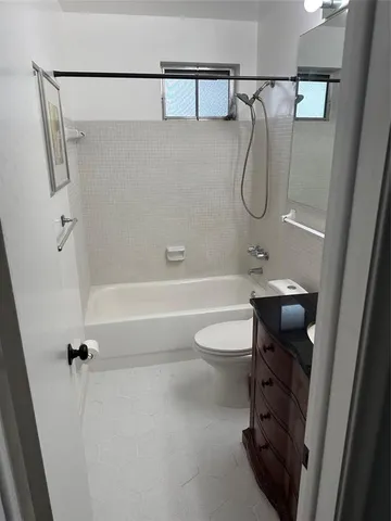 a bathroom with a granite countertop bathtub shower sink vanity and toilet