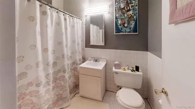 a white toilet sitting next to a white sink and a shower curtain