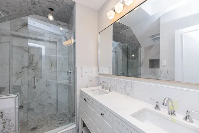 a bathroom with a sink vanity granite shower and a mirror