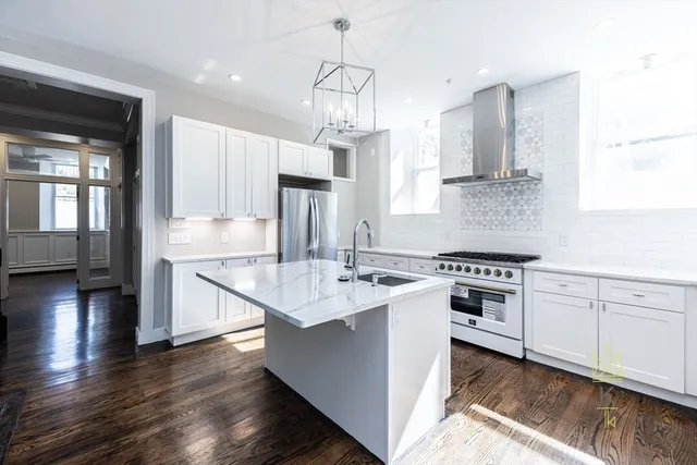 a kitchen with stainless steel appliances a sink stove and wooden floor