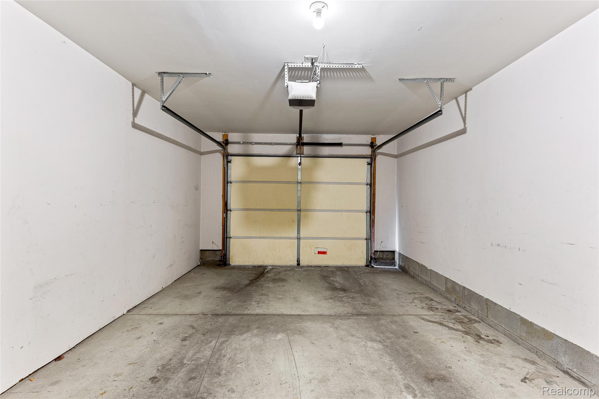 3553 Oakmonte Boulevard Rochester, MI 48306 - Photo 33 of 42 Single-car garage with a paneled door, concrete flooring, and a ceiling-mounted garage door opener