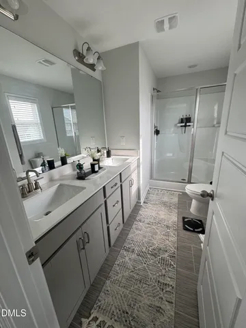 a bathroom with a double vanity sink a mirror a toilet and a shower
