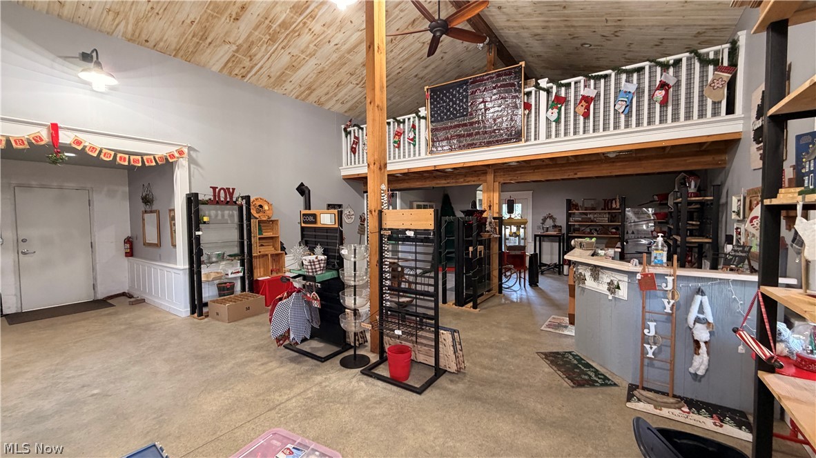 5620 Streeter Road Mantua, OH 44255 - Photo 39 of 45 Spacious interior featuring a high vaulted ceiling with exposed wood beams, a prominent mezzanine level with a white railing, and industrial-style concrete flooring