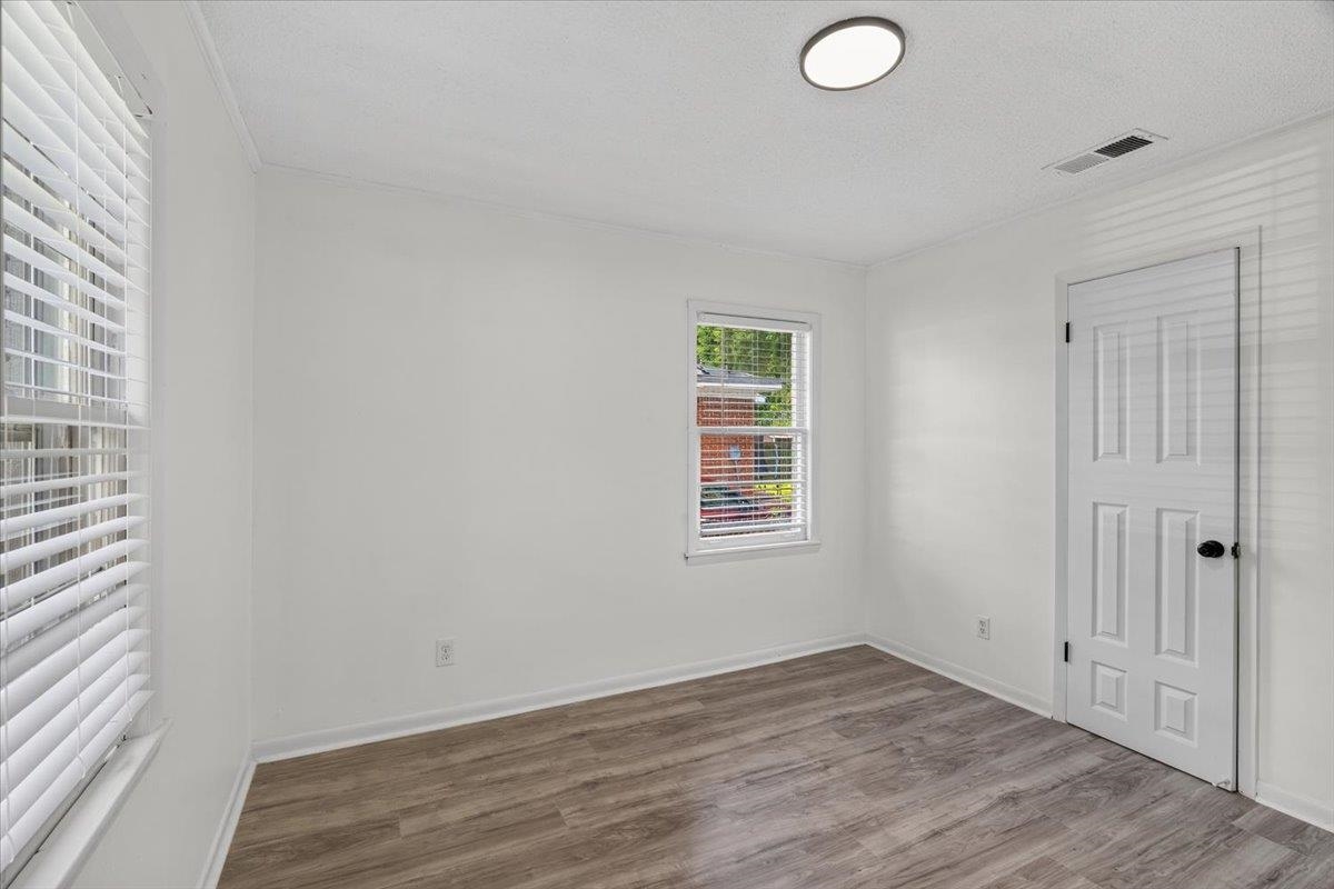 2717 Merle Street Memphis, TN 38118 - Photo 8 of 18 Room with wood-finish flooring, two windows with blinds, a white paneled door, and a flush-mount ceiling light
