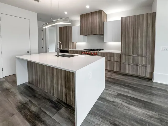 a kitchen with kitchen island granite countertop a sink and a refrigerator