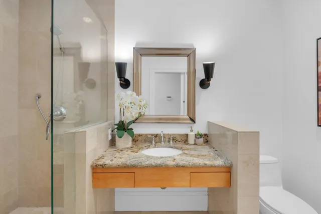 a bathroom with a granite countertop sink a toilet and a mirror