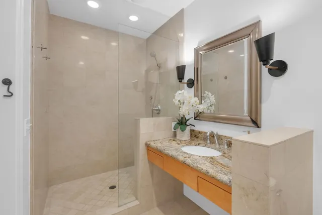 a bathroom with a granite countertop sink a mirror and shower