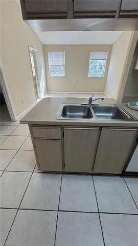 a view of a sink and dishwasher with wooden cabinets