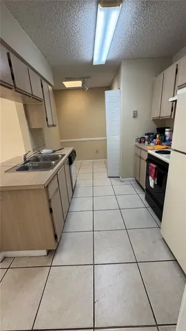 a kitchen with granite countertop a stove a sink and a refrigerator