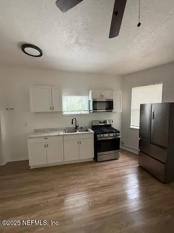 a large kitchen with stainless steel appliances granite countertop a stove a sink and a refrigerator