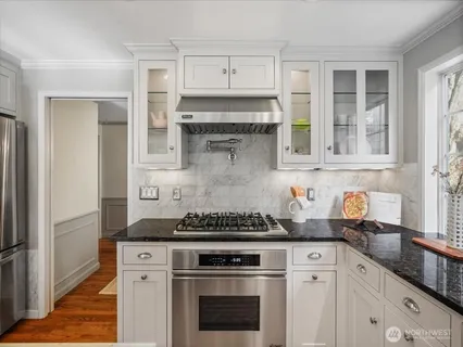 a kitchen with stainless steel appliances granite countertop white cabinets and a stove