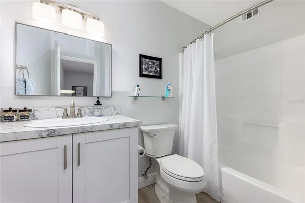 a bathroom with a granite countertop toilet sink and mirror