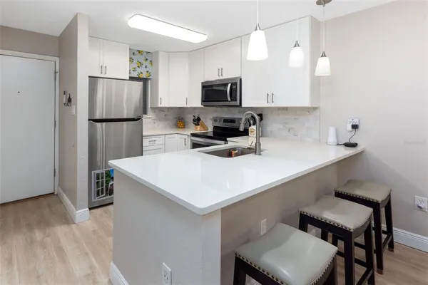 a kitchen with a sink a microwave a refrigerator and chairs