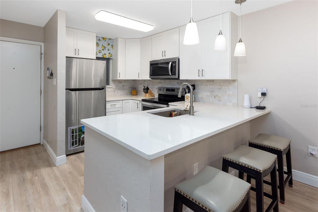 75 Southeast 16th Avenue, Unit A101 Gainesville, FL 32601 - Photo 6 of 24 a kitchen with a sink a microwave a refrigerator and chairs