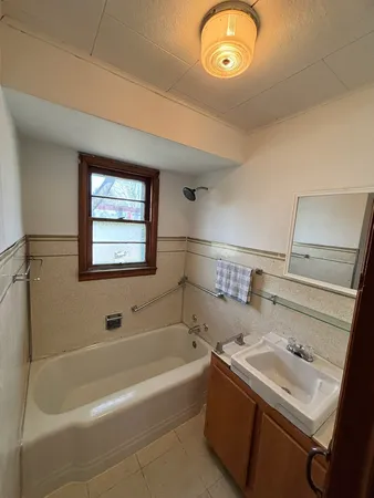 a bathroom with a tub sink and mirror