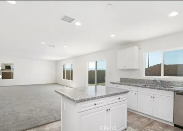 a kitchen with granite countertop a sink and white cabinets