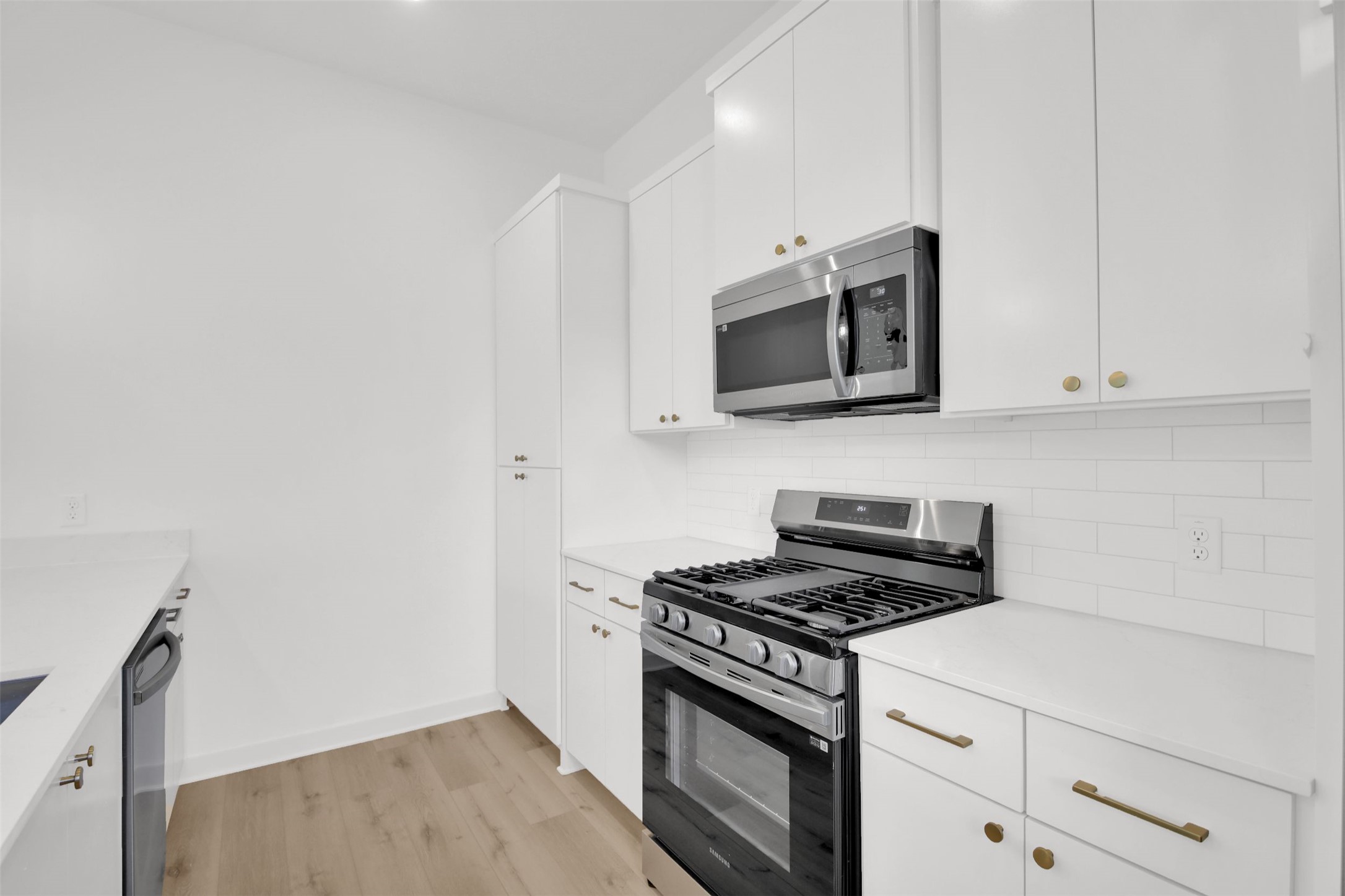 7208 Providence Avenue, Unit 1 Austin, TX 78752 - Photo 9 of 26 The kitchen features white cabinetry, white countertops, and stainless steel appliances, including a microwave and a range