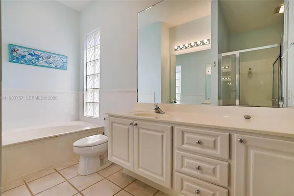 a spacious bathroom with a granite countertop sink toilet a mirror and a bathtub