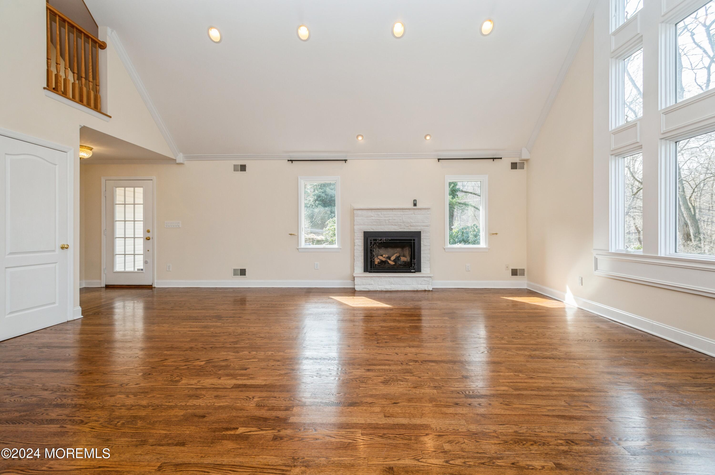 26 Van Brackle Road Holmdel, NJ 07733 - Photo 4 of 36 an empty room with wooden floor and a fireplace