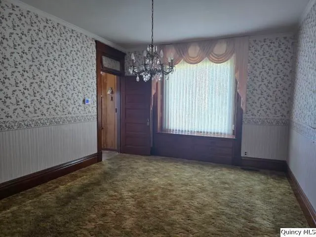 an empty room with windows and chandelier