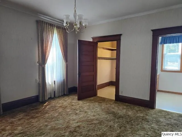 an empty room with windows and chandelier fan