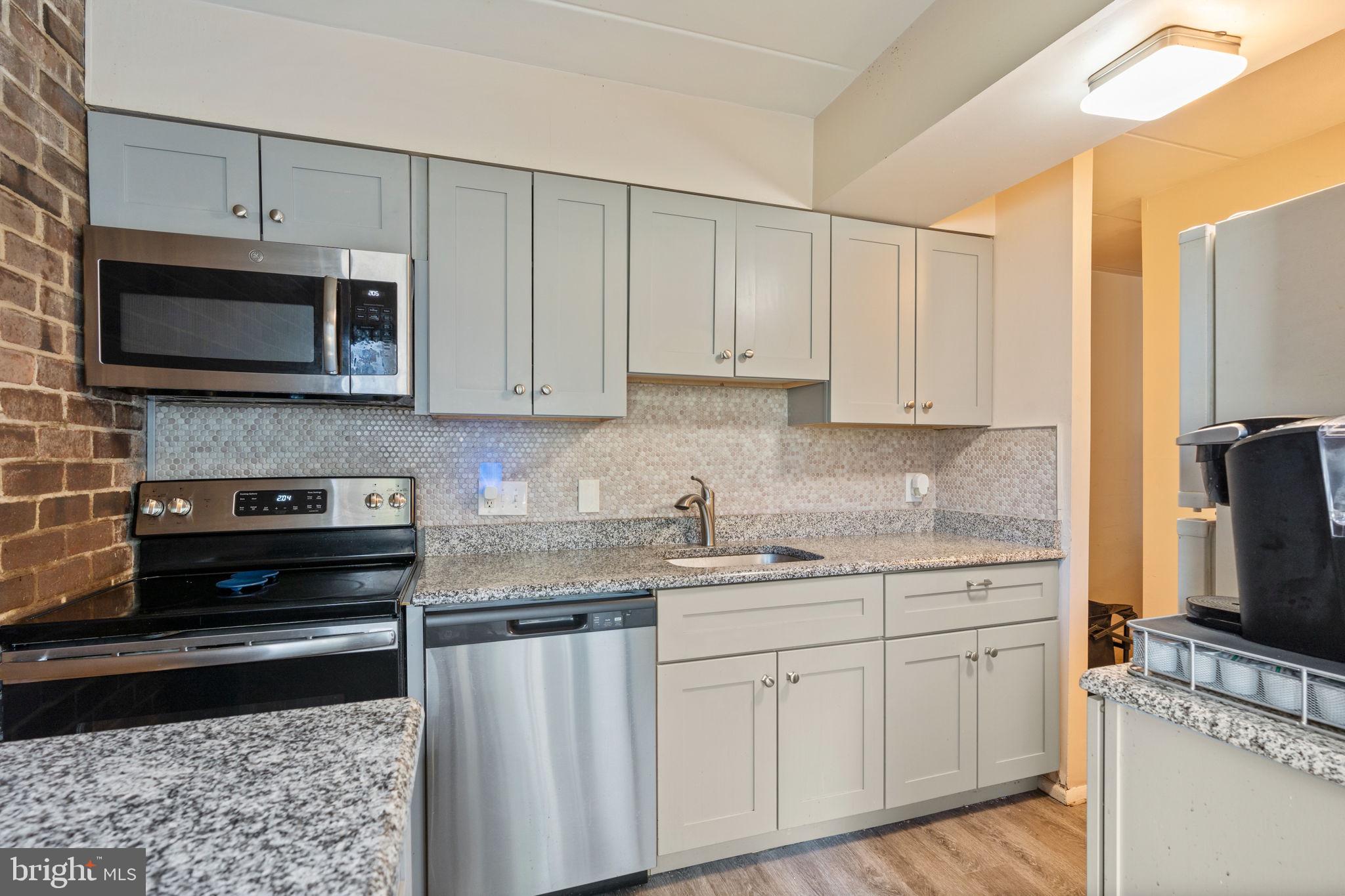 5382 Smooth Meadow Way, Unit 4 Columbia, MD 21044 - Photo 5 of 23 a kitchen with stainless steel appliances granite countertop a stove a sink and a microwave