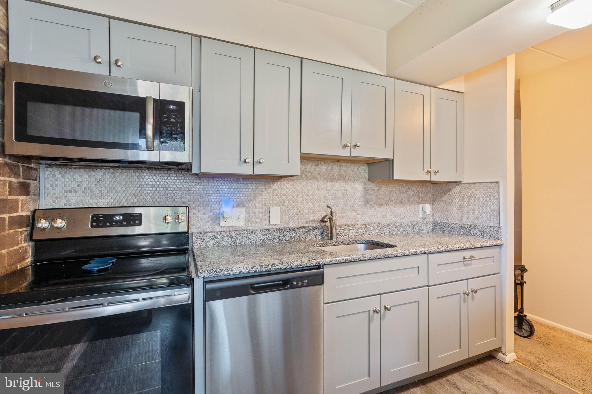 5382 Smooth Meadow Way, Unit 4 Columbia, MD 21044 - Photo 6 of 23 a kitchen with stainless steel appliances granite countertop a sink a stove and microwave