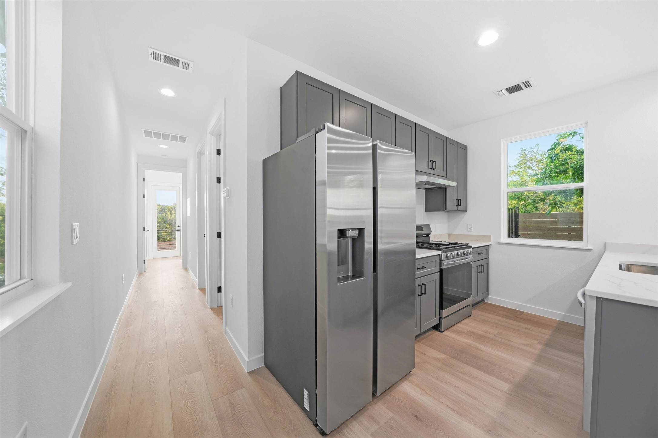 2212 Yellow Jacket Lane, Unit 2 Austin, TX 78741 - Photo 12 of 25 Modern kitchen featuring stainless steel appliances, gray cabinetry, light countertops, and wood-finish flooring