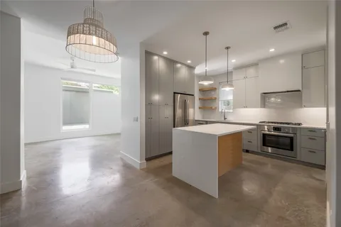 a large kitchen with stainless steel appliances kitchen island granite countertop a refrigerator a stove and a sink