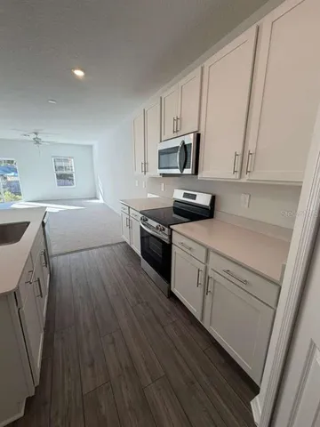 a kitchen with cabinets wooden floor and stainless steel appliances