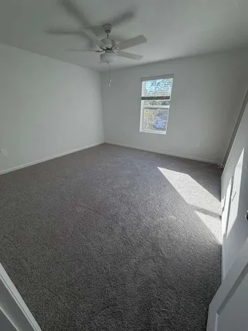 an empty room with windows and ceiling fan