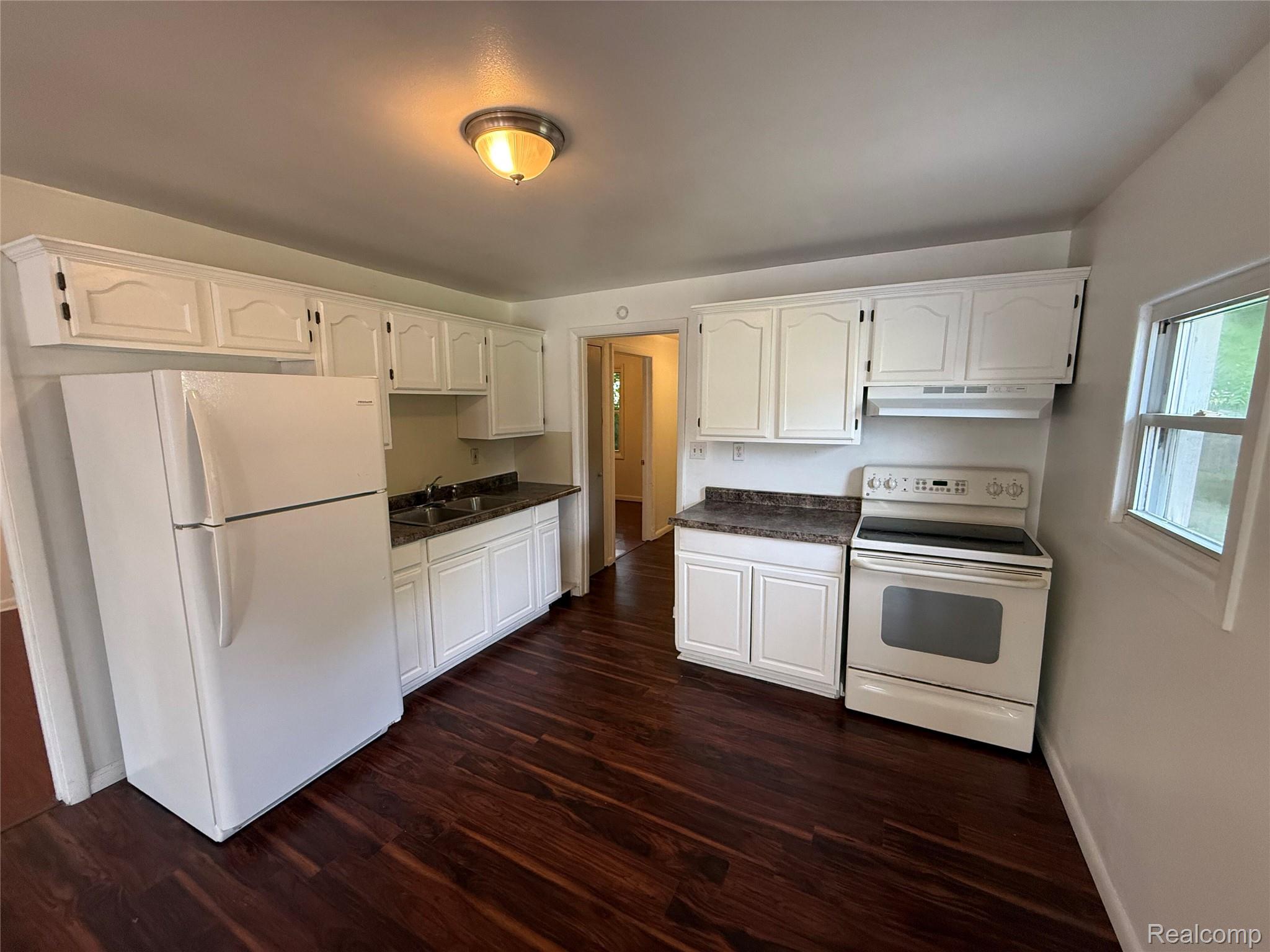 2194 East Bristol Road Burton, MI 48529 - Photo 5 of 13 Kitchen featuring wood-finish flooring, white cabinetry, dark speckled countertops, and a white appliance suite