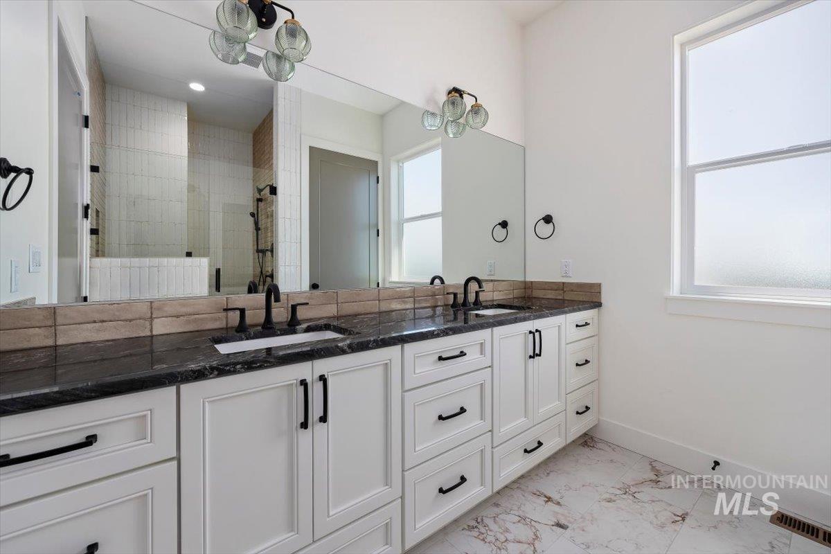563 Moonstone Road Kimberly, ID 83341 - Photo 23 of 48 Dual vanity with dark countertops and white cabinetry, featuring matte black fixtures and hardware, large wall-mounted mirror, and tile flooring