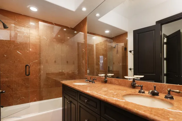 a bathroom with a double vanity sink a mirror and a bathtub