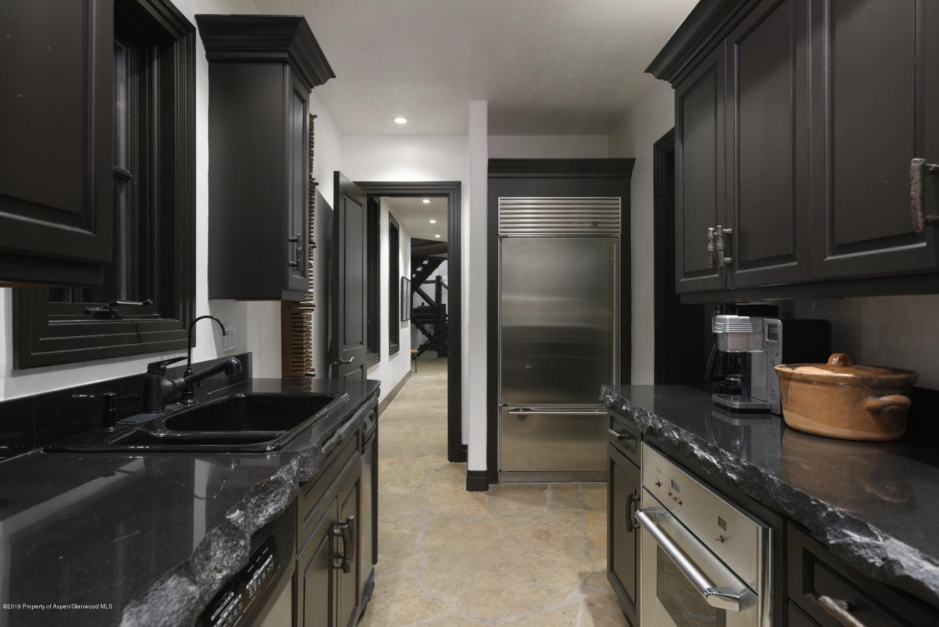 450 Smuggler Mountain Road Aspen, CO 81611 - Photo 24 of 37 a kitchen with granite countertop a sink stove and refrigerator