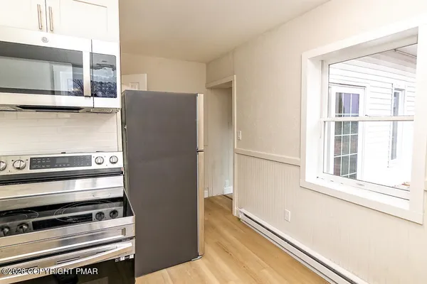 a view of a kitchen with stainless steel appliances wooden floor and a window