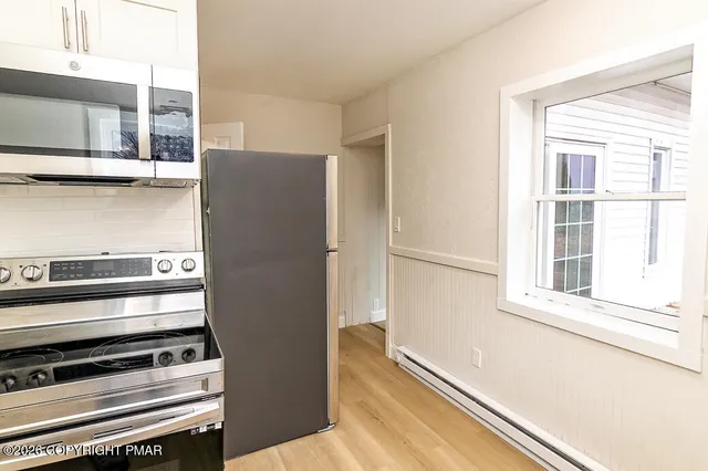 a view of a kitchen with stainless steel appliances wooden floor and a window